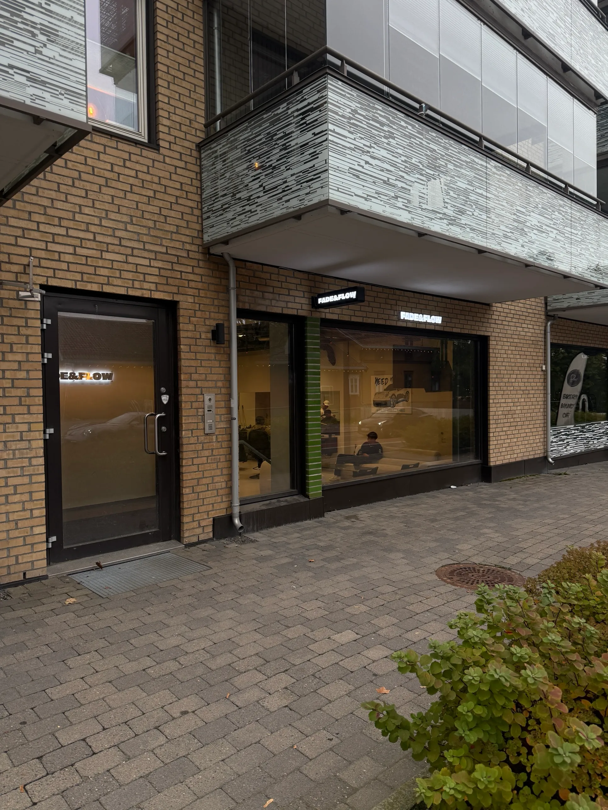 Inngangen til Fade & Flow på Sandaker, med logoen lyst opp over vinduet mot gaten.