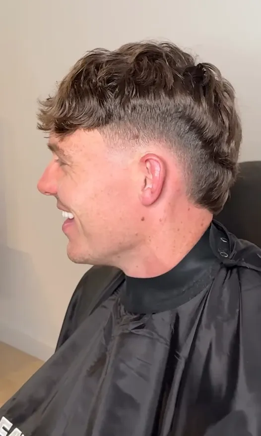 Sideprofil av en herreklipp med skarp fade og tekstrik topp.