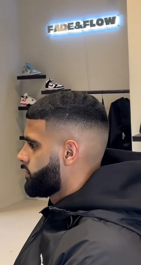 Sideprofil av en herreklipp med fade og velstelt skjegg, fotografert i salongen.